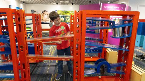 a boy explores an exhibit of balls and ramps