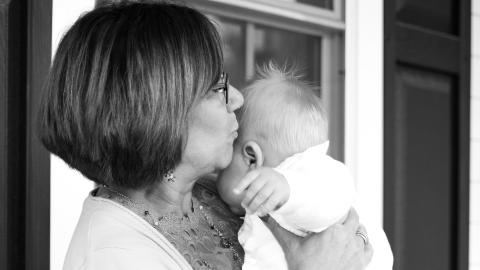 A grandmother holds her granddaughter and kisses her head